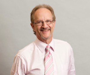 A man in a pink shirt and a pink and white tie.