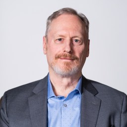 Patrick McNamara with a beard and a blue shirt.