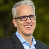 A man wearing glasses and a blue shirt.