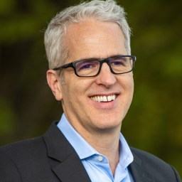 A man wearing glasses and a blue shirt.