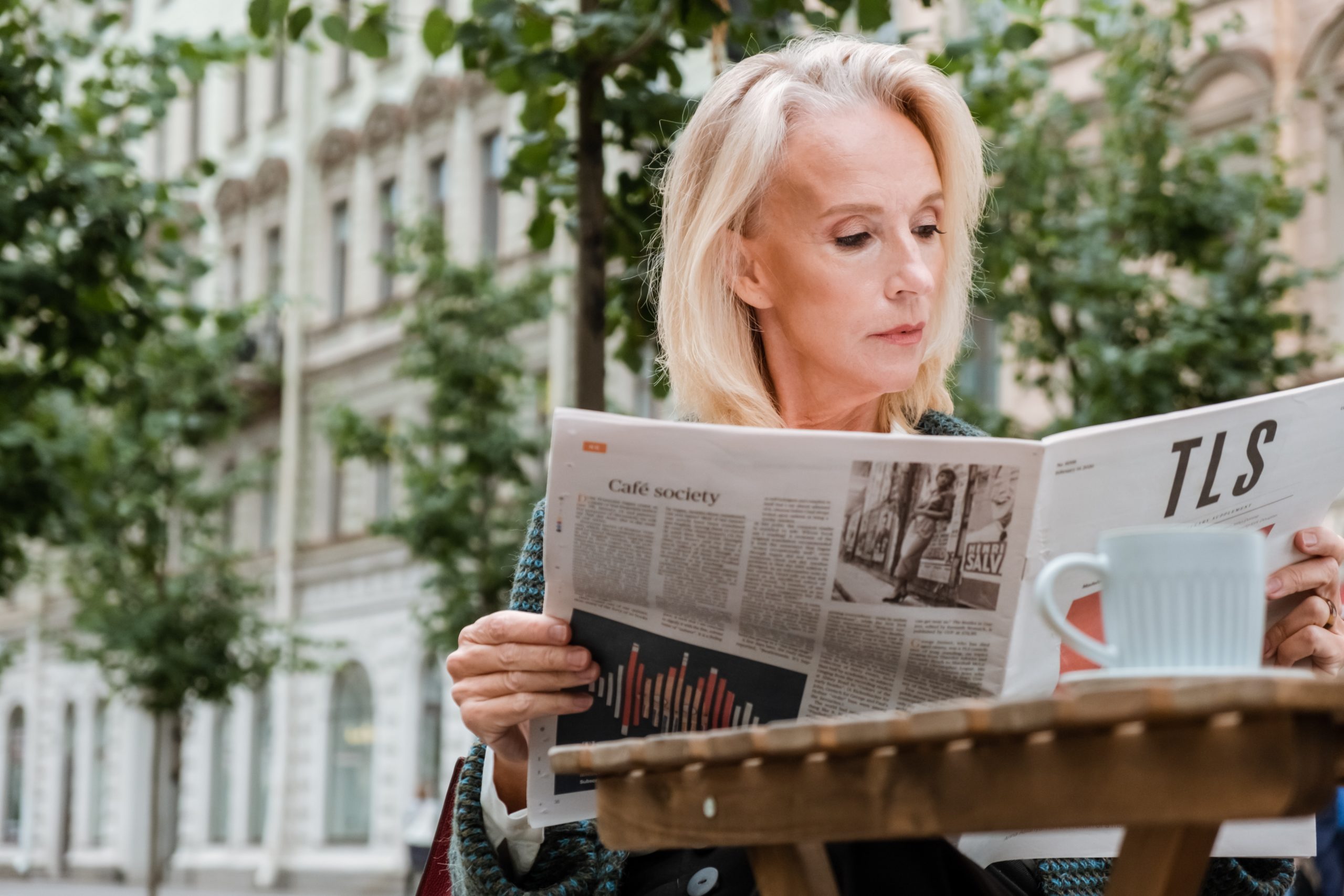 A woman reads a newspaper.