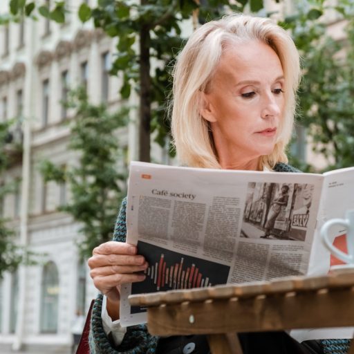 A woman reads a newspaper.