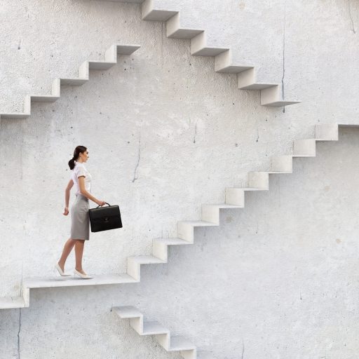 A businesswoman climbs a staircase as symbol of self-development and career growth.