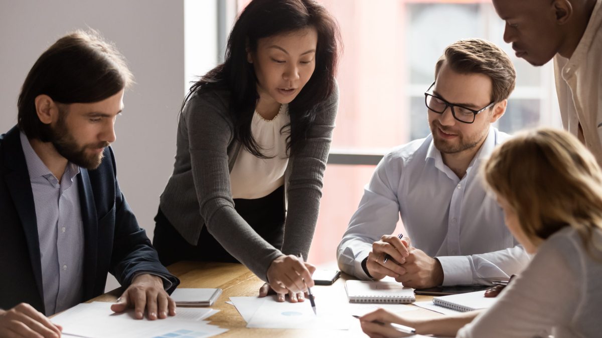 A woman business leader takes her team through a report.