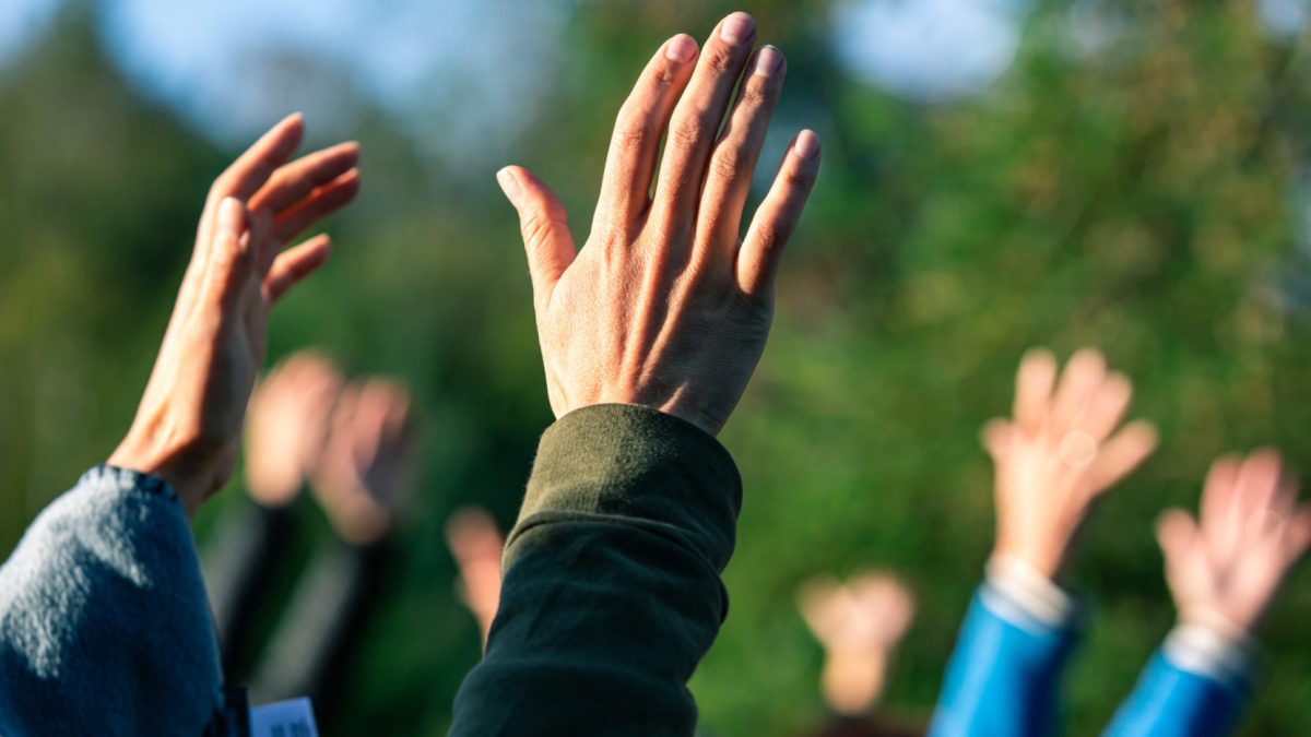 Group of people putting their hands up in the air.