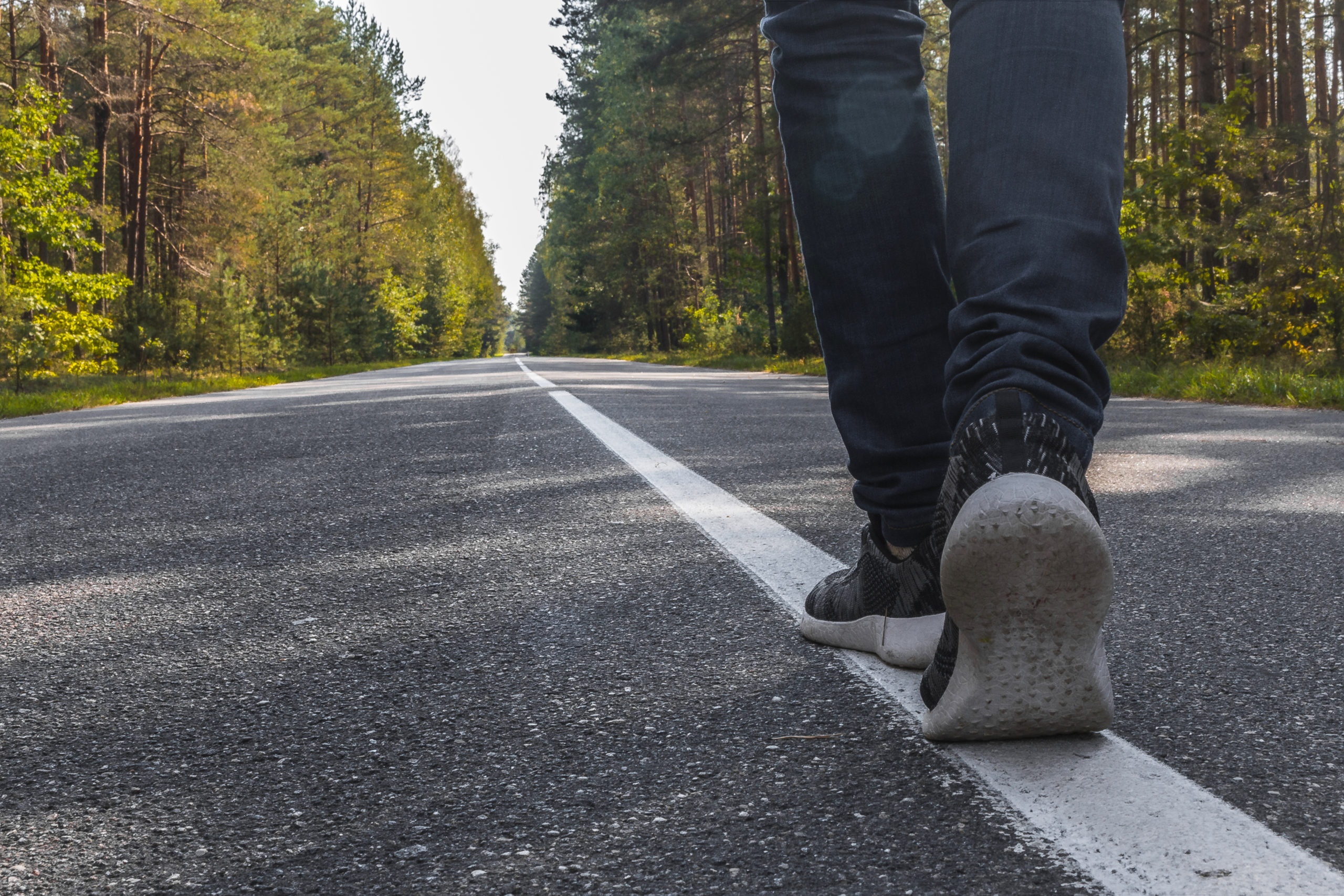 Someone takes a step forward along a forest road.