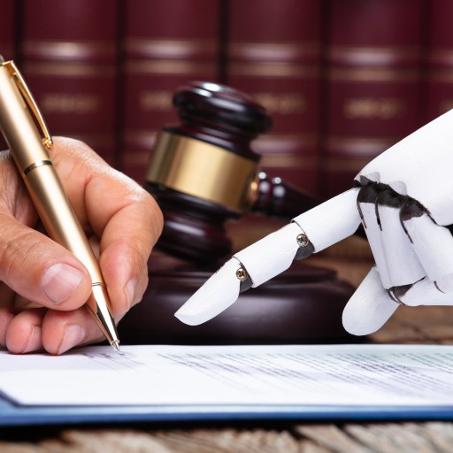 A robot hand helps a human hand sign a law document.