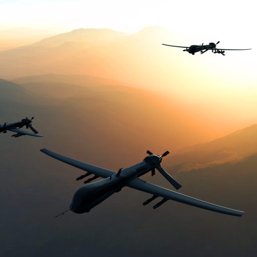 Three drones fly through sky with the sun behind them.