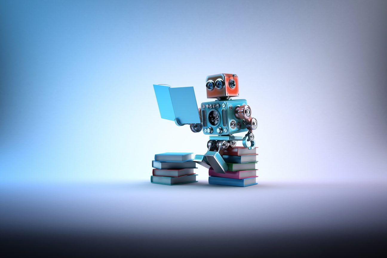 A robot sits on a pile of books and reads.