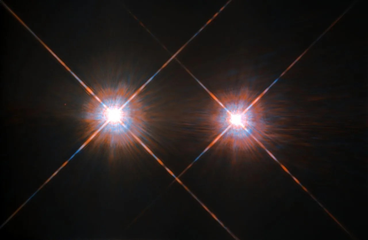 Two bright, star-like points of light with visible diffraction spikes are set against a dark background.
