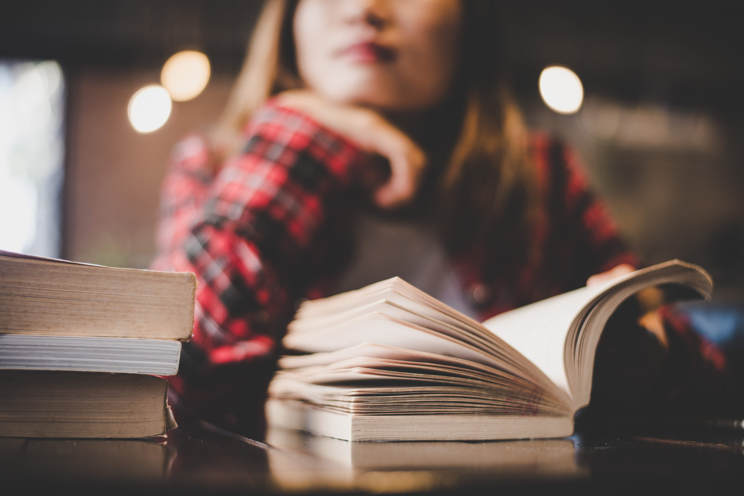 A woman stares pensively while reading a book.