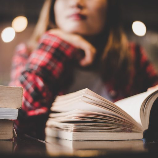 A woman stares pensively while reading a book.