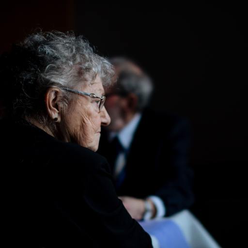 an older woman against a dark background illustrating aging loneliness and regret