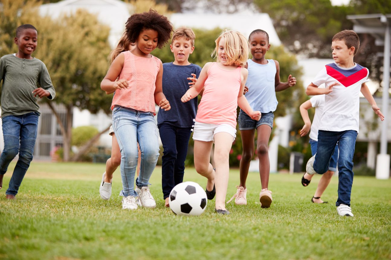 Children playing soccer in a field.