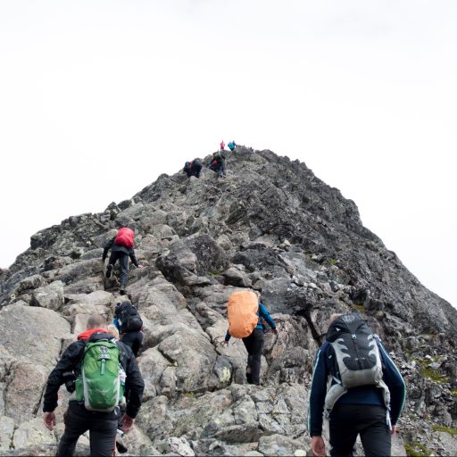People climbing up a mountain following a leader