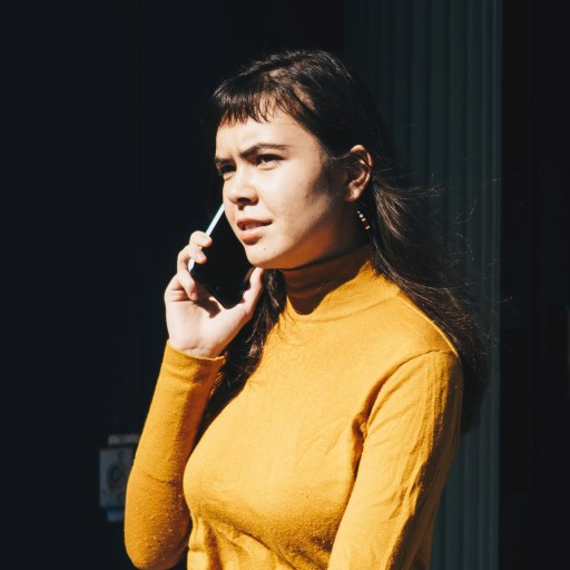 A woman in a yellow shirt talking on the phone.