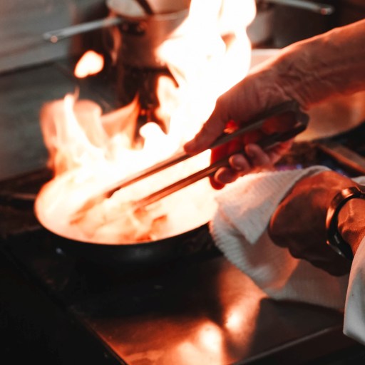 A person turning meat in a frying pan illustrating why deep fried turkeys explode