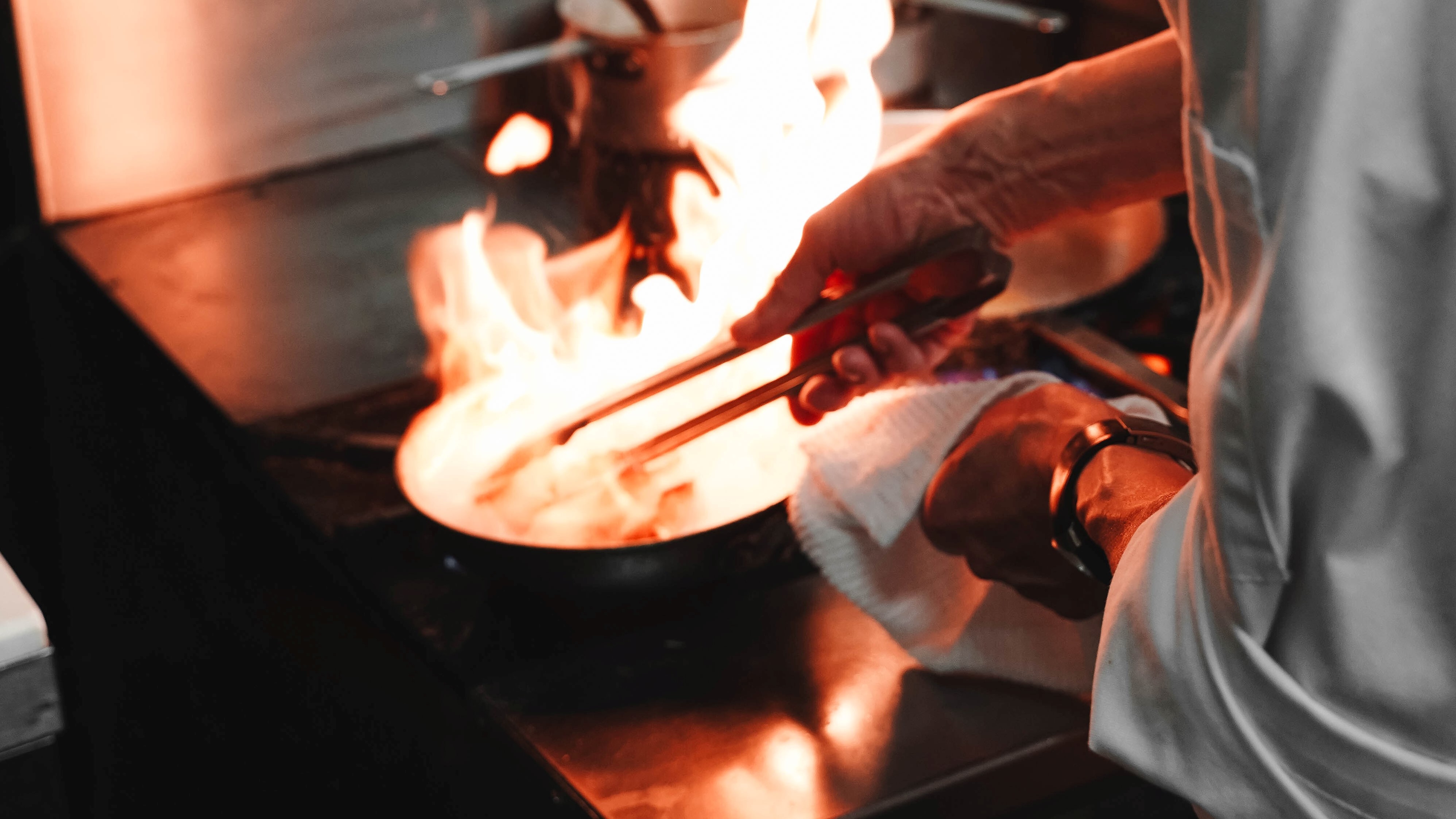 A person turning meat in a frying pan illustrating why deep fried turkeys explode
