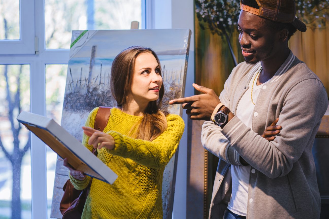 A young couple discuss a painting.