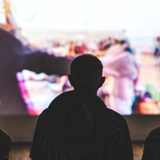 Silhouettes of three people watching a screen.