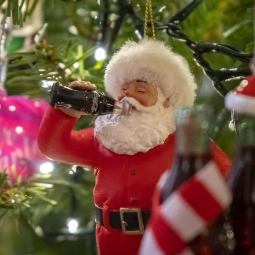A Santa Claus Christmas tree decoration drinking cola.