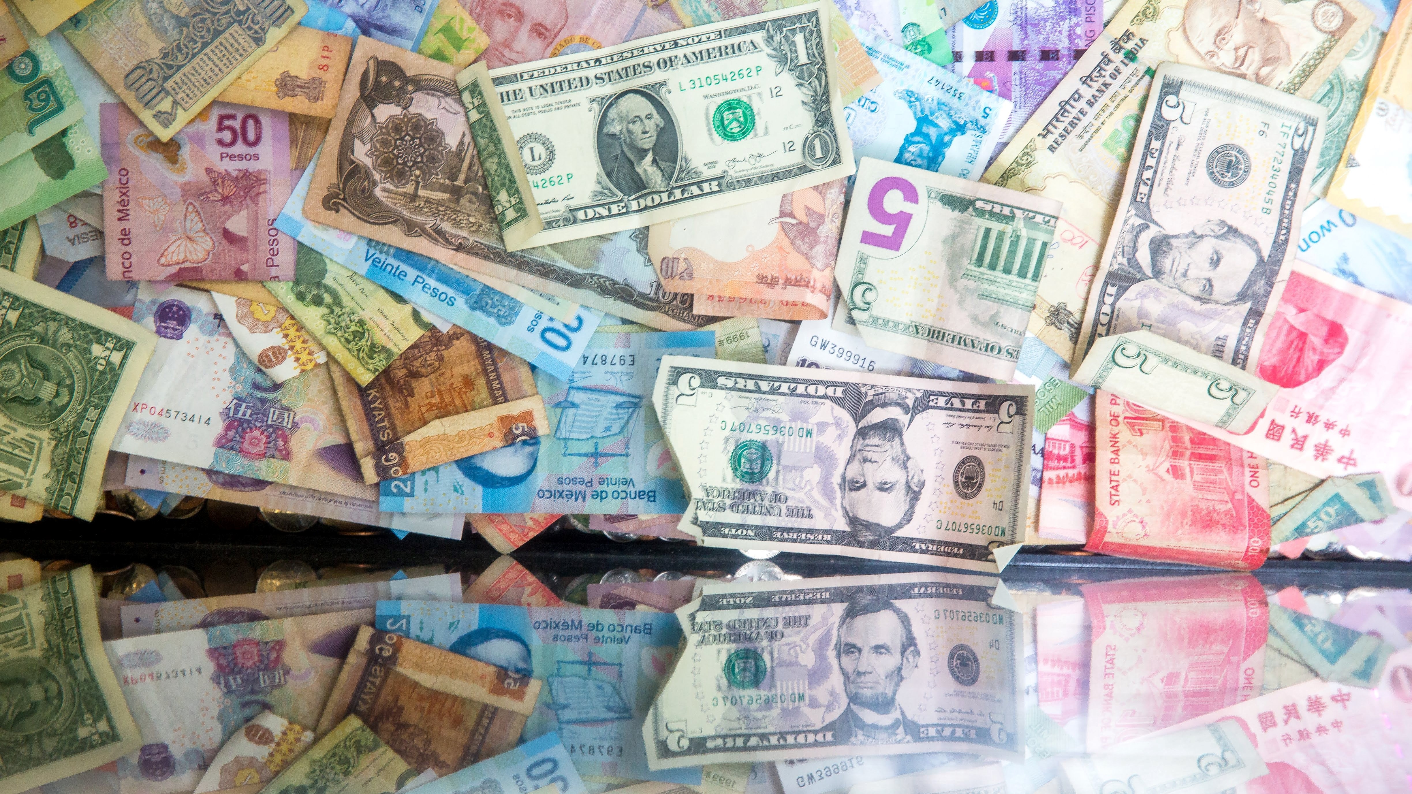 Inflation: An image of money taped to a wall and reflected by a glass surface.