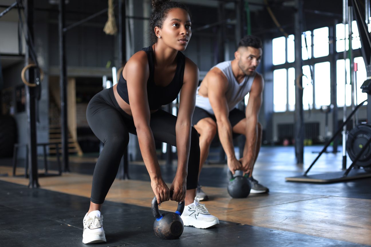 A couple lifting kettlebells during their workout.