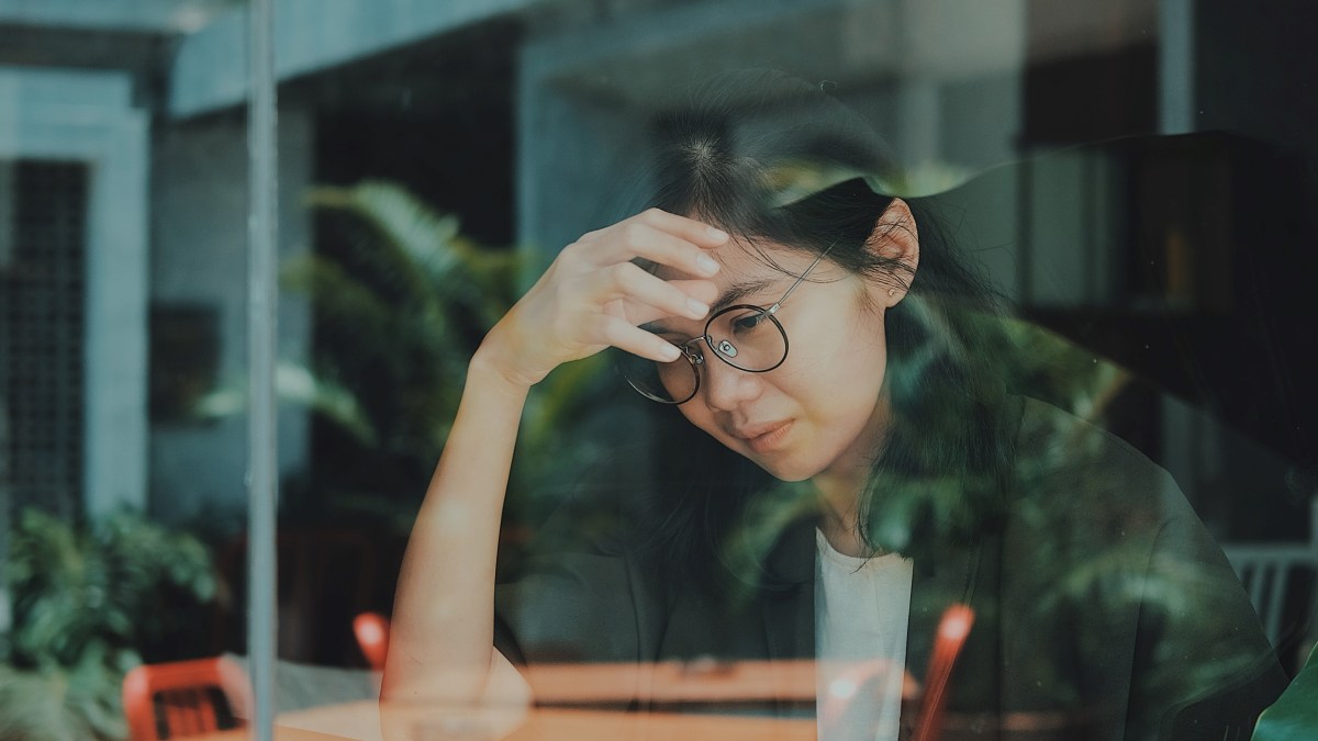 A woman behind a window looking regretful