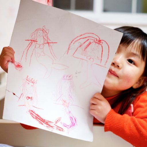 A child showing their drawing to the camera