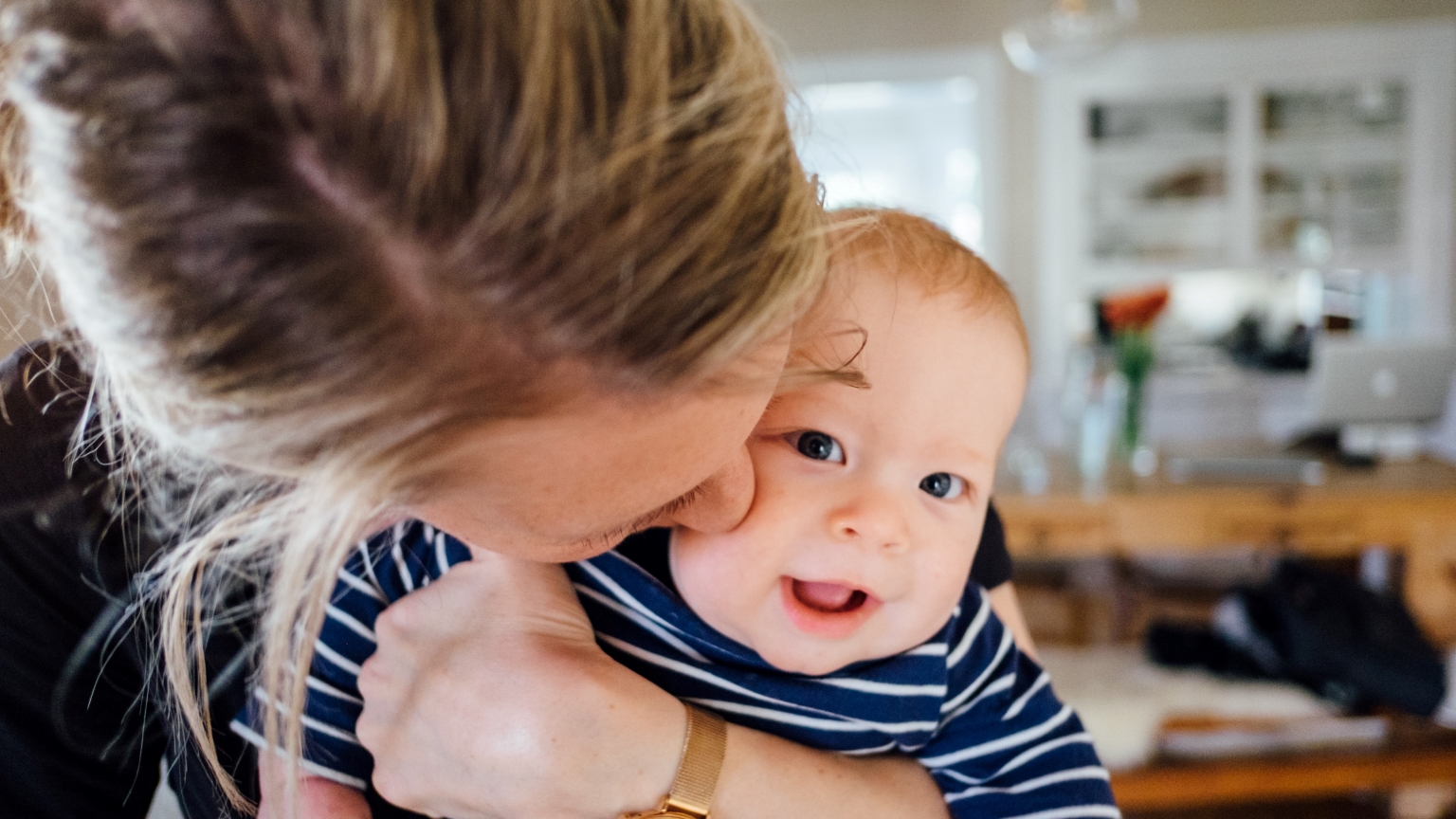 Closeup of a baby being kissed by his mother.