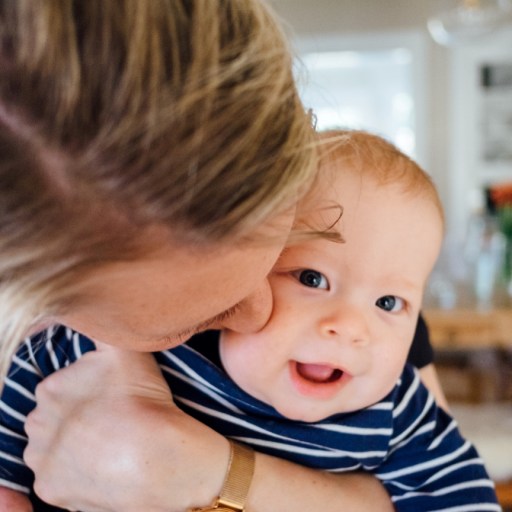 Closeup of a baby being kissed by his mother.