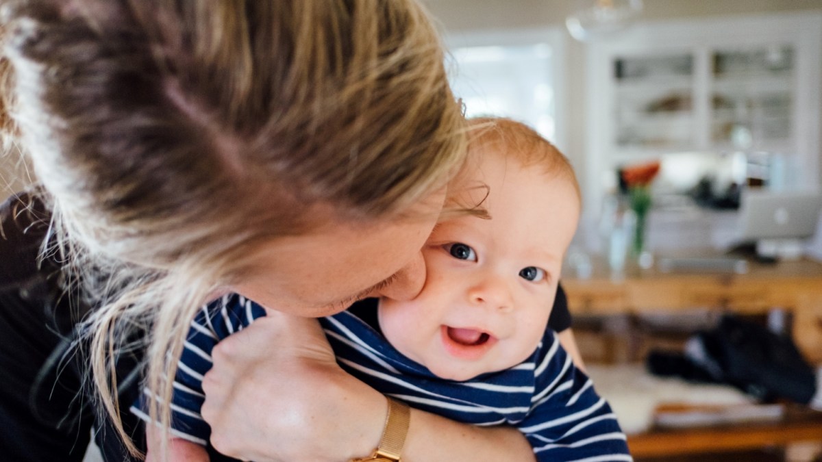 Closeup of a baby being kissed by his mother.