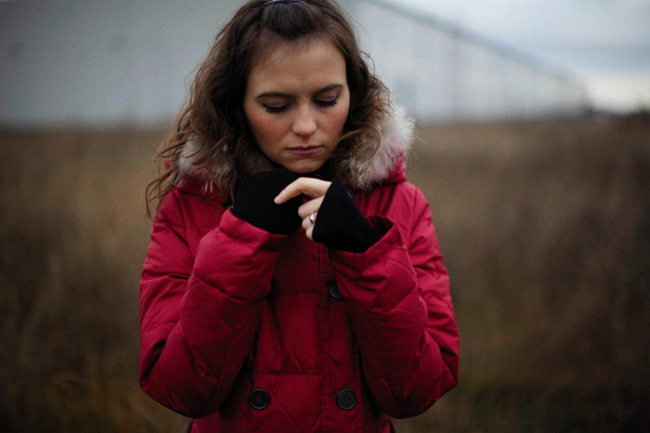 A woman stands in the cold in a red jacket.