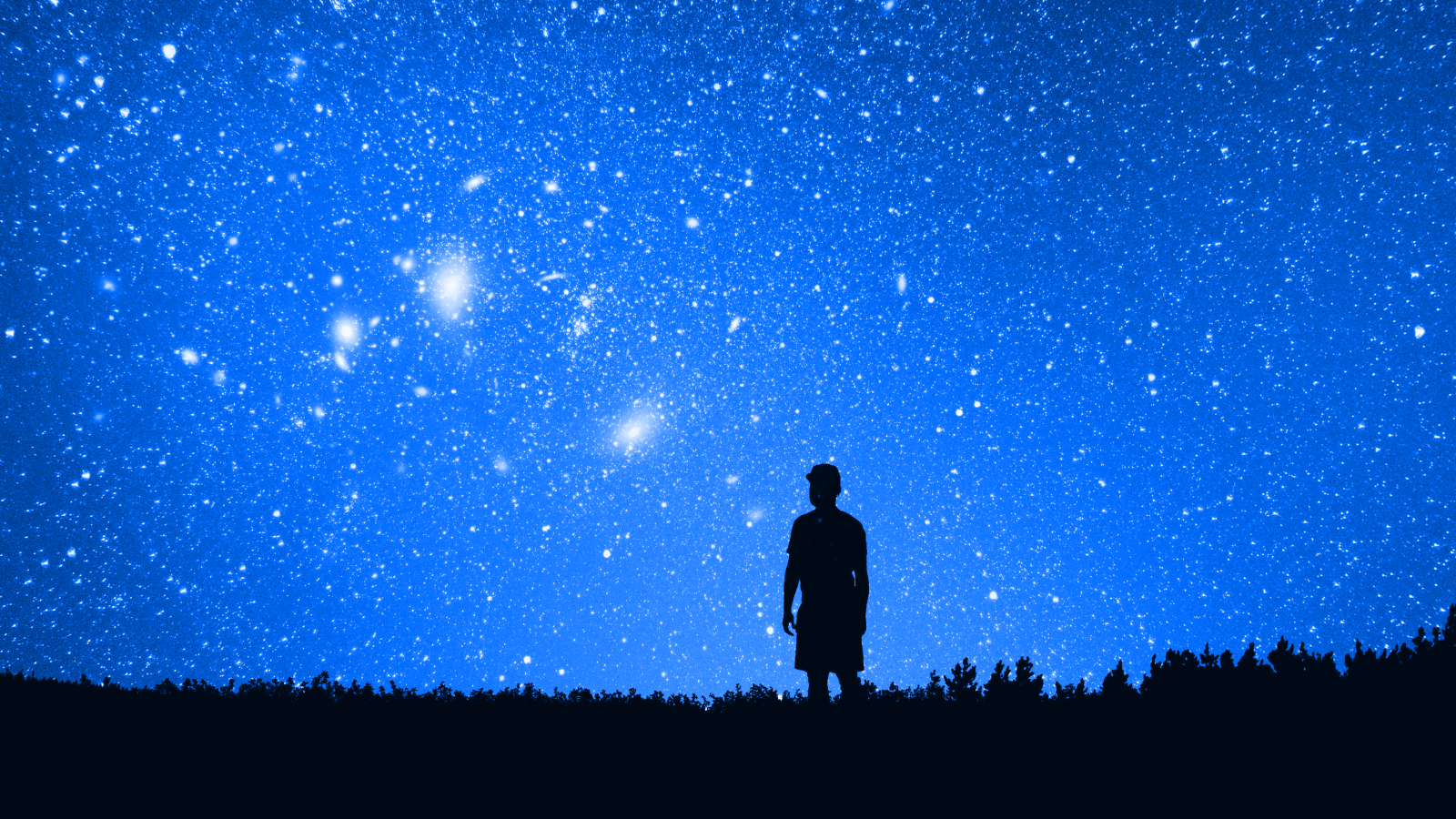 Silhouette of a person standing on a field at night, gazing at a clear sky filled with stars and glowing celestial objects, evoking the wonder described by Jim Al-Khalili.