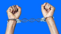 Two hands in handcuffs, connected by a DNA double helix chain, symbolize genome blindness against a solid blue background.