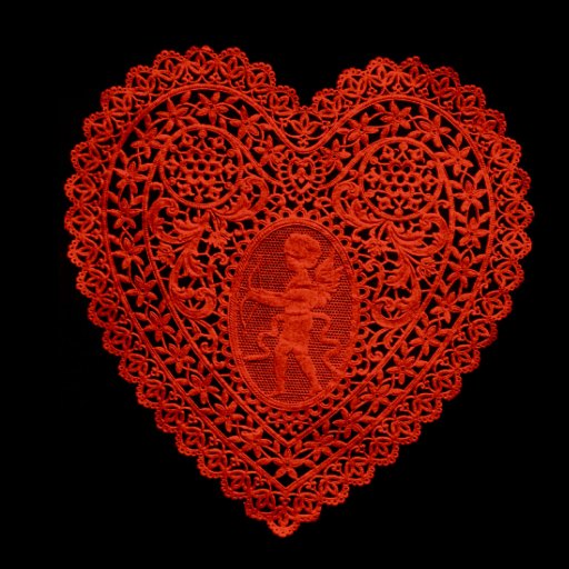 A red, intricately patterned lace heart with a floral border and a cherub design in the center, set against a black background.