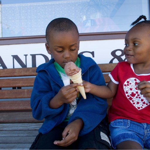 A boy and girl share an ice cream cone