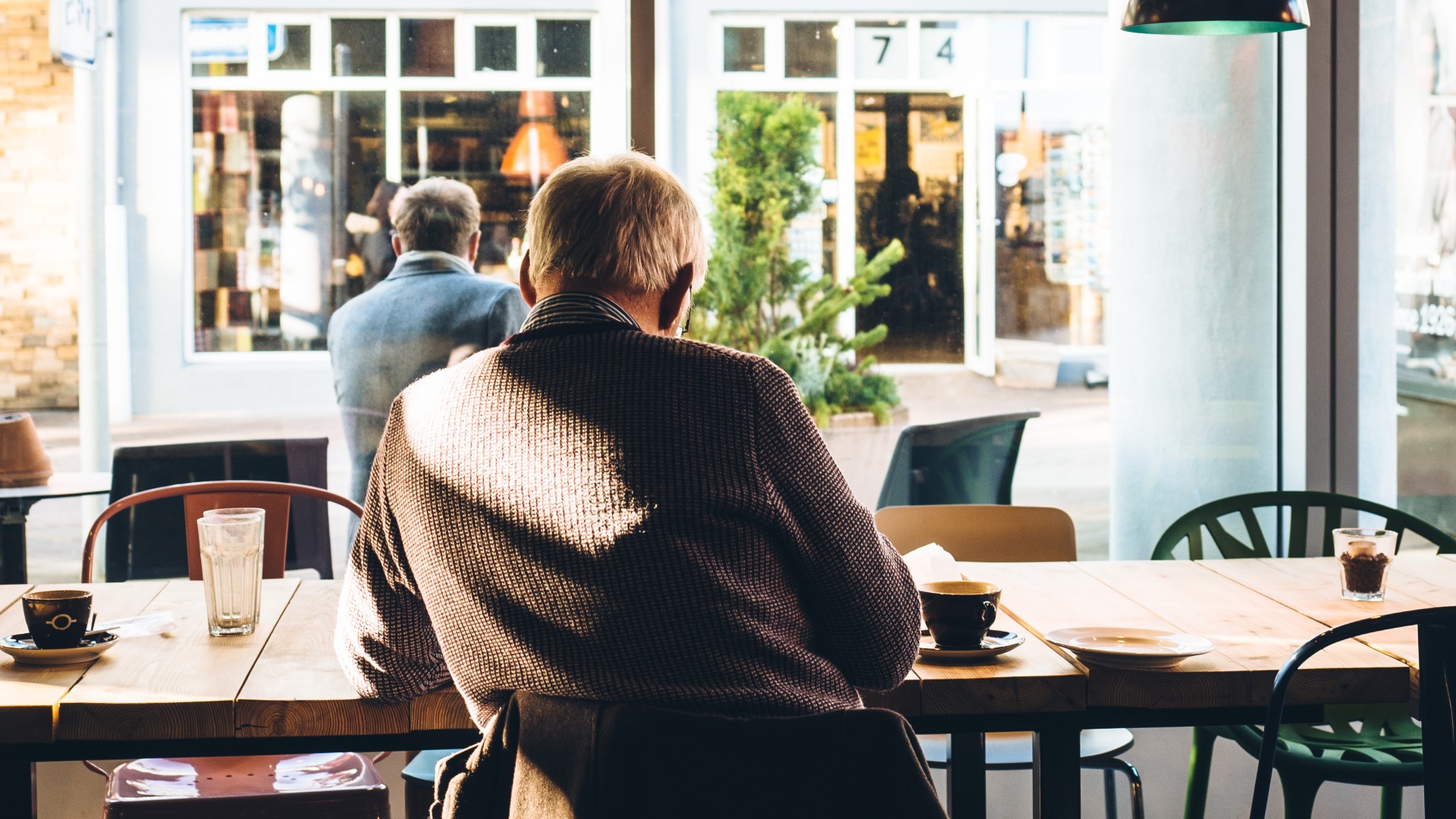 An old man sits idly in a cafe.