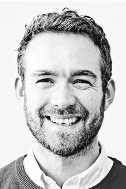 a black and white photo of a smiling man.