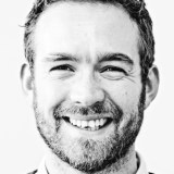 a black and white photo of a smiling man.