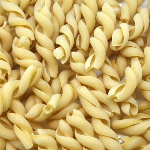 a pile of uncooked macaroni shells on a white surface.