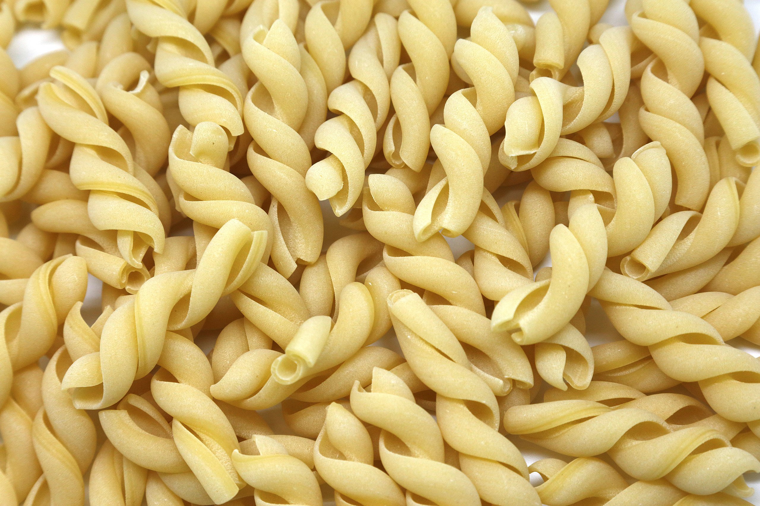 a pile of uncooked macaroni shells on a white surface.