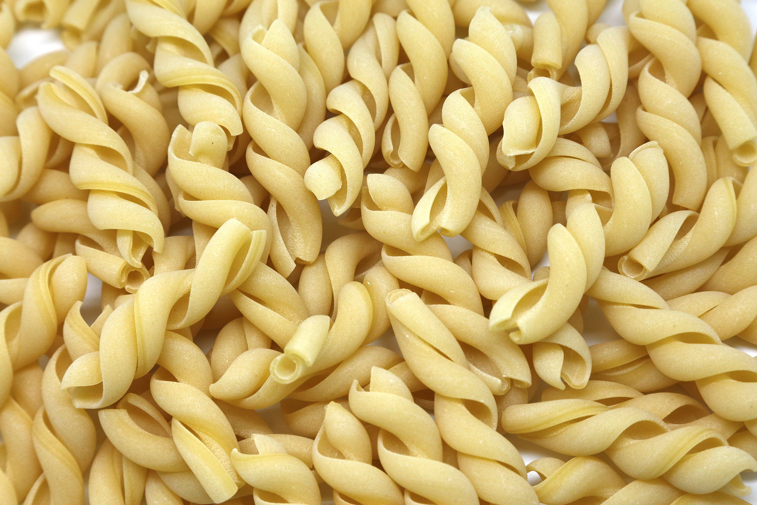 a pile of uncooked macaroni shells on a white surface.