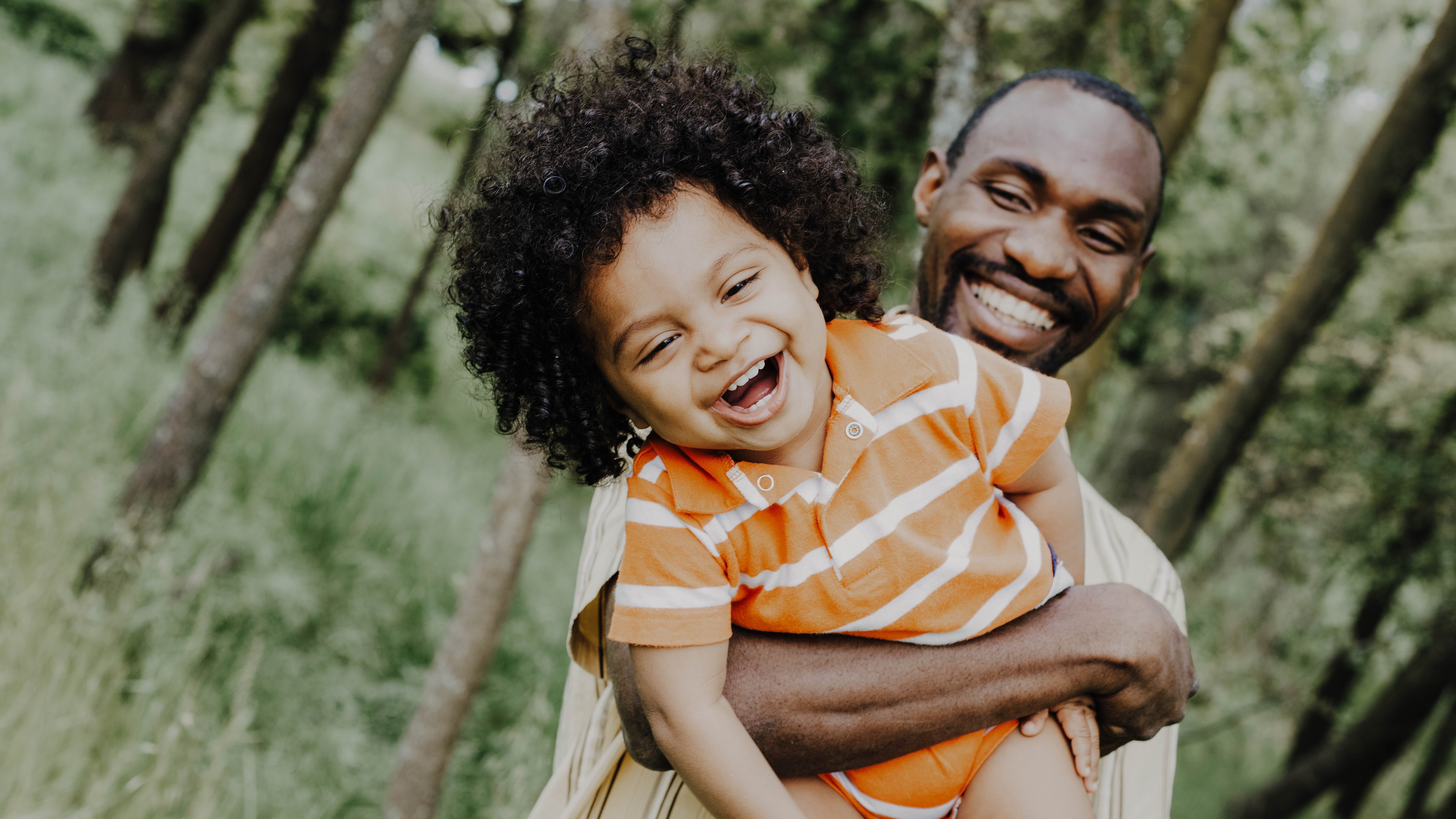 A father plays holds his smiling child.