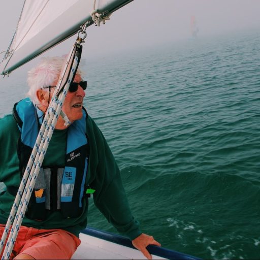 a man sitting on the bow of a sailboat.