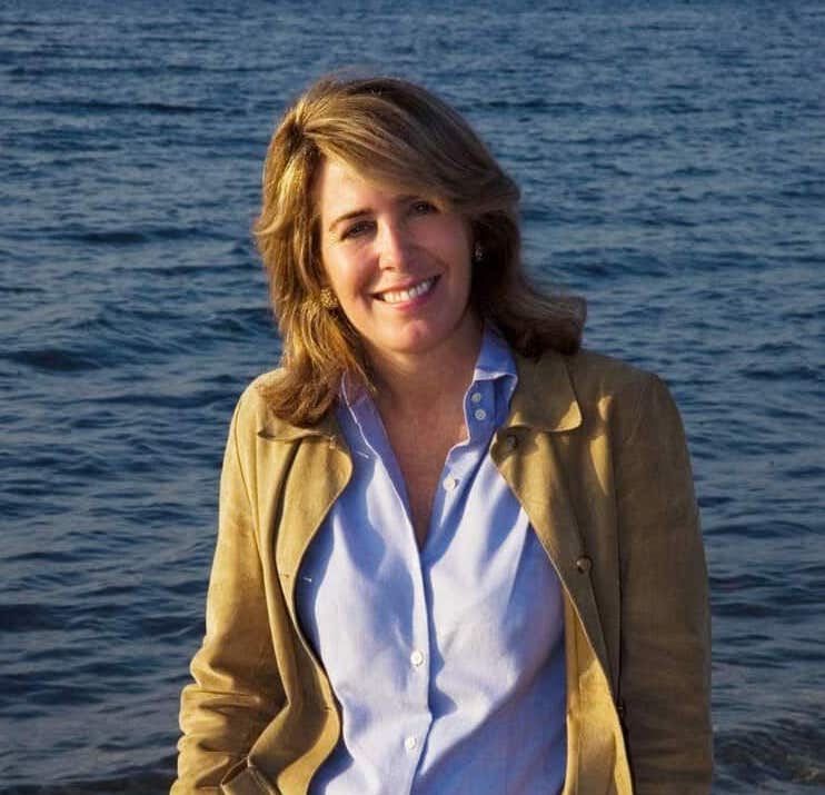 a woman standing on a beach next to a body of water.