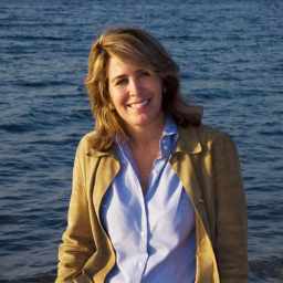 a woman standing on a beach next to a body of water.
