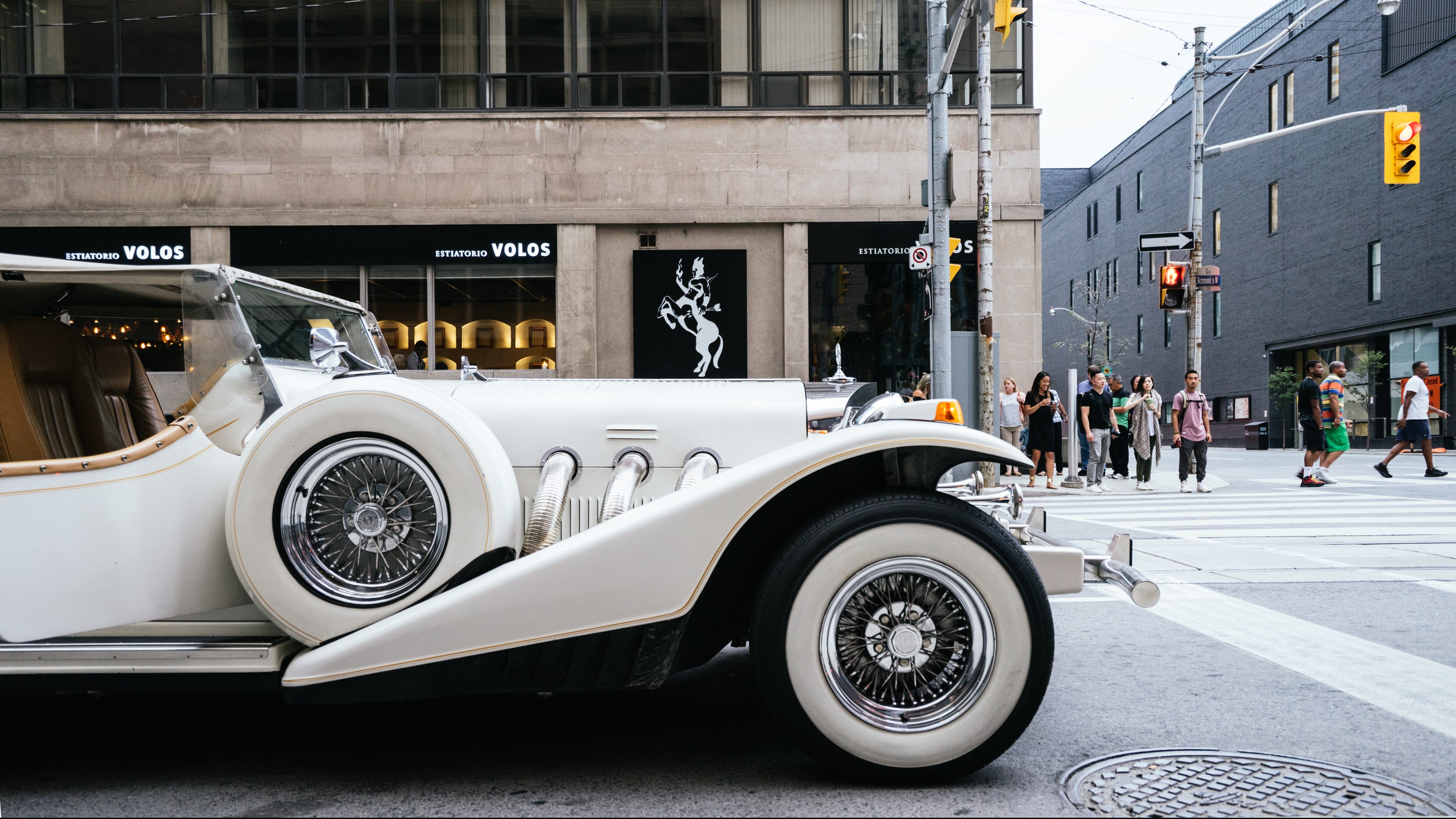 A white, luxury car stopped at an intersection.