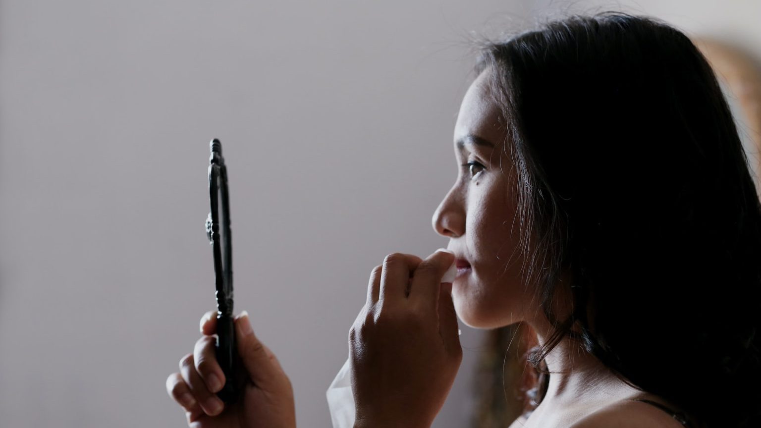 a woman holding a mirror up to her face.