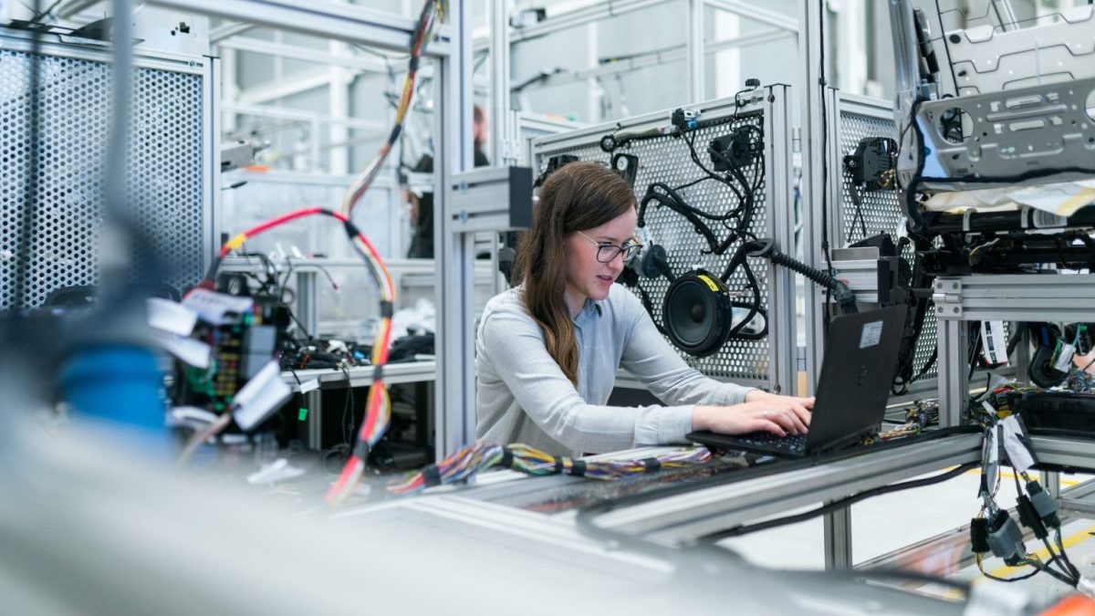 a woman working on a laptop in a factory.